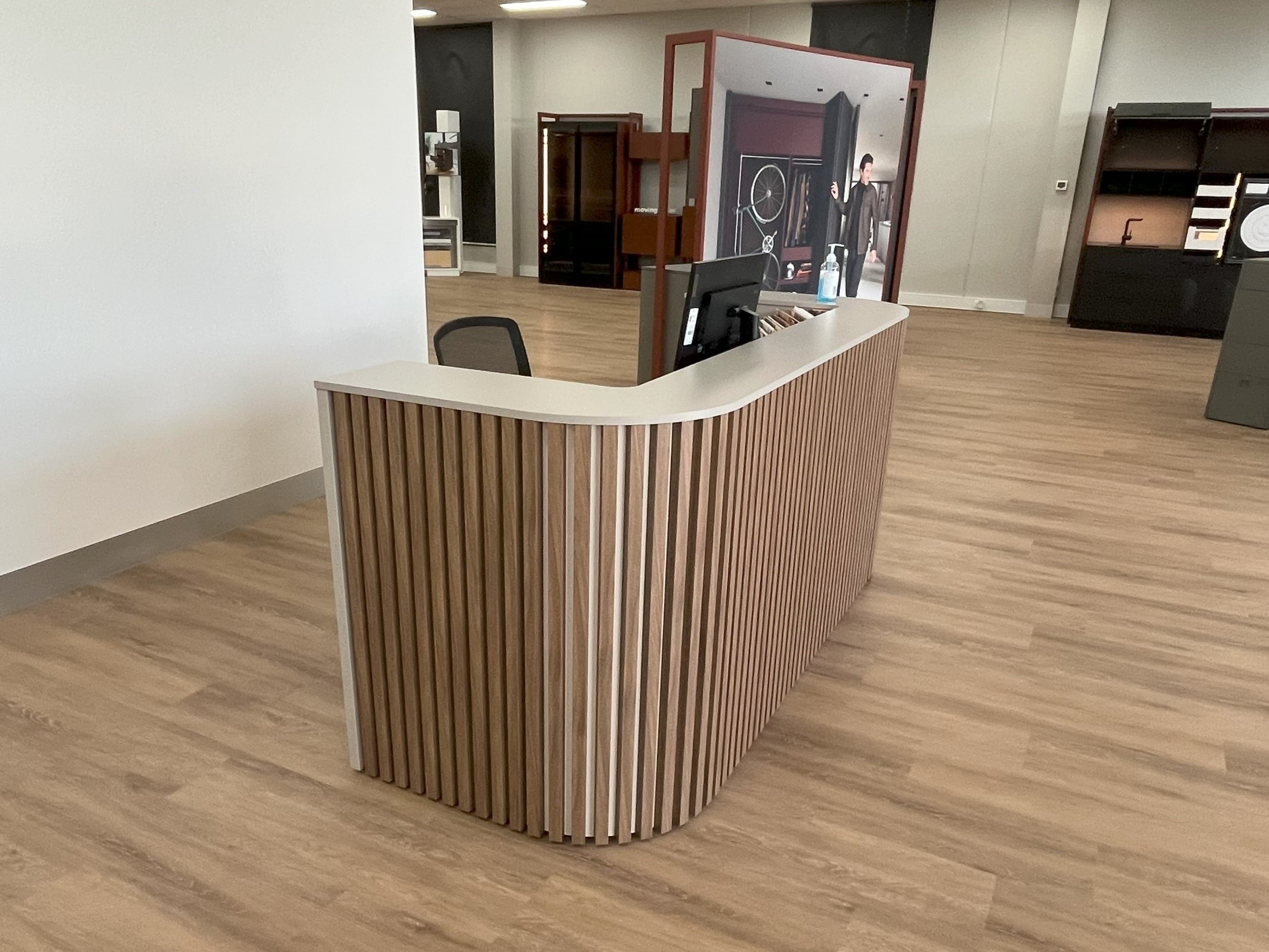 Curved reception counter with a vertical timber batten front and stone top in the Blum showroom
